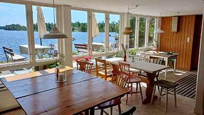 Sjöholmens kafé med bord inomhus och utsikt över sjön.