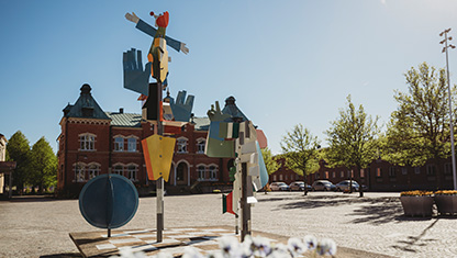 Kyrktorget i Värnamo med Tingshuset i bakgrund och i förgrunden är det konstverk och blommor.